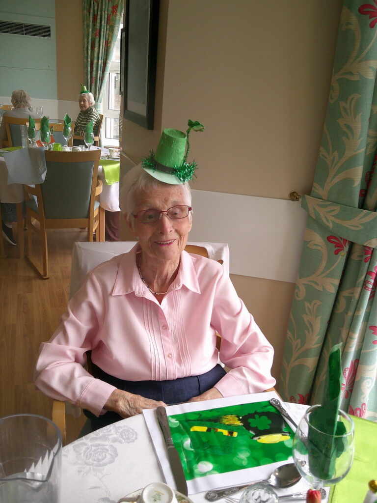 Resident enjoying St Patrick's day meal wearing celebration hat.