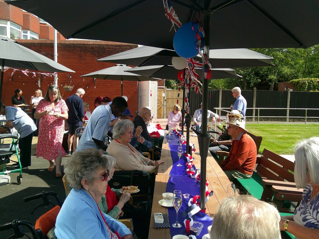 Residents enjoying VE Day 80th with cream tea and prosecco
